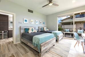 Ein Schlafzimmer mit einem großen Bett, zwei Nachttischen, einem Deckenventilator und Blick auf den Balkon.