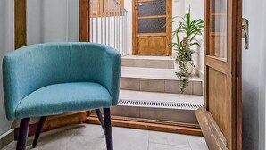 A teal chair in a room with a view of a courtyard featuring a wooden door, a potted plant, and a tiled floor. - SPACIOUS HOUSE IN HISTORIC CENTER WITH MAGNIFICENT VIEWS (Sagunt)