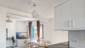 A modern kitchen with a black countertop, white cabinets, and a dining area with wooden chairs and a table. - SPACIOUS HOUSE IN HISTORIC CENTER WITH MAGNIFICENT VIEWS (Sagunt)