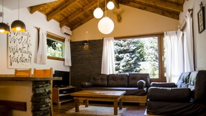 Ein gemütliches Wohnzimmer mit Kamin aus Stein, einem Holztisch, einer Ledersofa und einer Wand als Steinakzent.