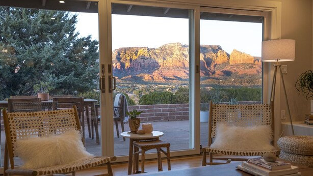 A cozy patio with wicker chairs, a small table, and a view of a mountainous landscape. - Sunrise to moonrise views. Hike/bike out the door. (Sedona)