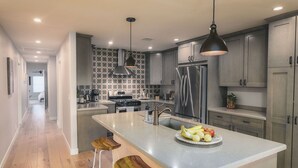 A modern kitchen with grey cabinets, a stainless steel refrigerator, and a central island with stools. - Sunrise to moonrise views. Hike/bike out the door. (Sedona)