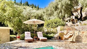 A pool area with lounge chairs, a hanging chair, and a stone wall. - Villa Eva Agni with private pool (Agni)