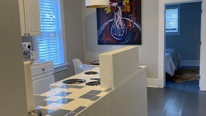 Une cuisine moderne avec un dosseret à carreaux, un îlot central et un tableau accroché au-dessus du plan de travail.