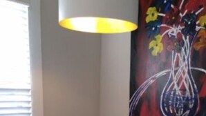 Un coin repas avec une table ronde, quatre chaises blanches et un tableau abstrait aux couleurs vives accroché au mur.