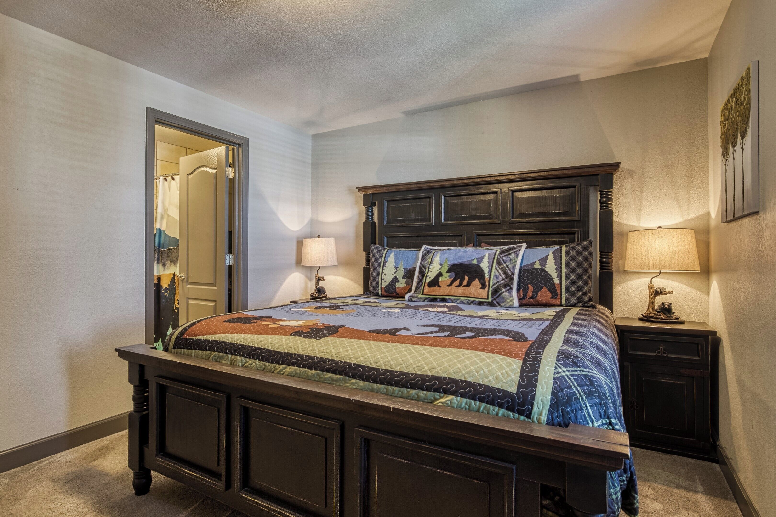 A bedroom with a large bed, dark wooden headboard, and a quilt with animal prints.