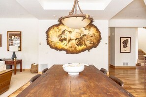 Enjoy a meal in this elegant dining area with a long table and unique light fixture.