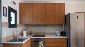 Eine Küche mit Holzausstattung, einem Edelstahlkühlschrank, einem Einbauofen und einem Spülbecken.