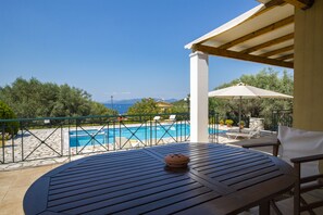 A patio with a view of a swimming pool and the sea.