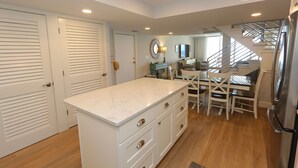 A kitchen with a marble countertop, white cabinets, and a stainless steel refrigerator. - Luxury 3BD Beachfront Living: La Playa 203D by RVA (Longboat Key)