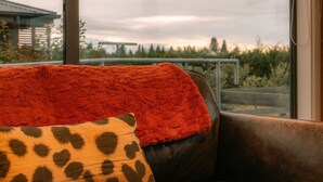 A room with a large window, a leather sofa, and a red blanket.