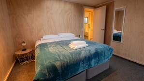 A bedroom with a bed, a bedside table, a mirror, and a skylight.
