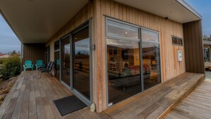 A modern building with a covered porch, large sliding glass doors, and a wooden deck.