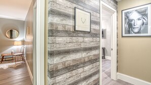 Ein Flur mit rustikaler Holzvertäfelung, einem Bild mit Hirschgeweih und einem gerahmten Porträt an der Wand.