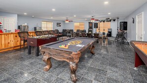 Quarto com mesa de bilhar, mesa de pebolim e área de bar.