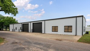 Um edifício industrial amplo com várias portas de garagem e janelas pequenas.