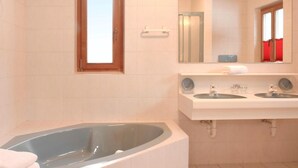 Ein Badezimmer mit einer großen Badewanne, zwei Waschbecken, einem Spiegel und einem Fenster.