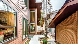 Ett modernt hus med stora fönster, en fasad av tegel och en liten trädgård framför huset.