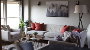 Ett vardagsrum med en soffa, fåtöljer, ett soffbord och en lampa.