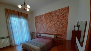 A bedroom with a bed, a nightstand, a dresser, a mirror, and a ceiling light fixture.