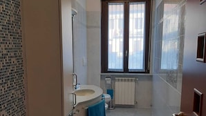 A bathroom with a toilet, sink, and a window with curtains.
