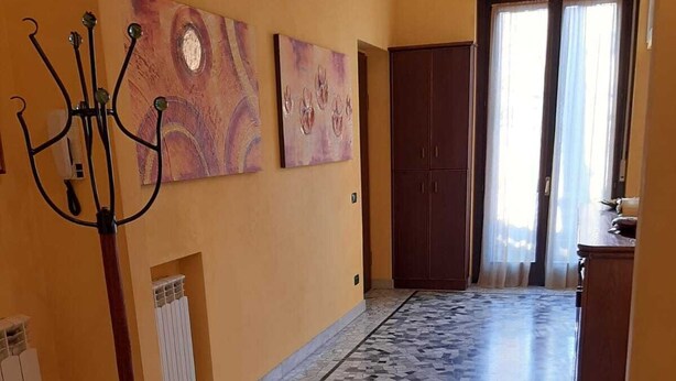 A hallway with a tiled floor, a coat rack, and two doors.