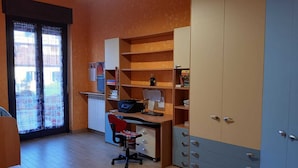 A study room with a desk, chair, shelves, and a wardrobe.