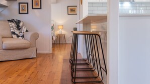 Una sala moderna con piso de madera, un sofá, una mesita auxiliar y un taburete de metal.
