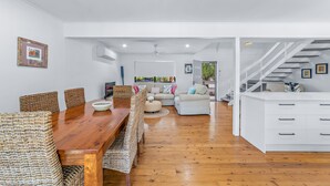 Un espacio habitable amplio con una mesa de comedor de madera, sillas de mimbre, un sofá y un armario blanco.