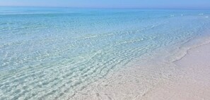 Een strand met helder, ondiep water en een zandstrand.