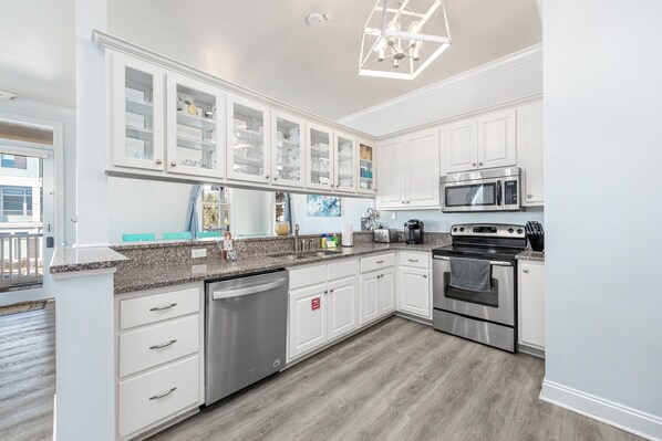 A modern kitchen with white cabinetry, stainless steel appliances, and a granite countertop.
