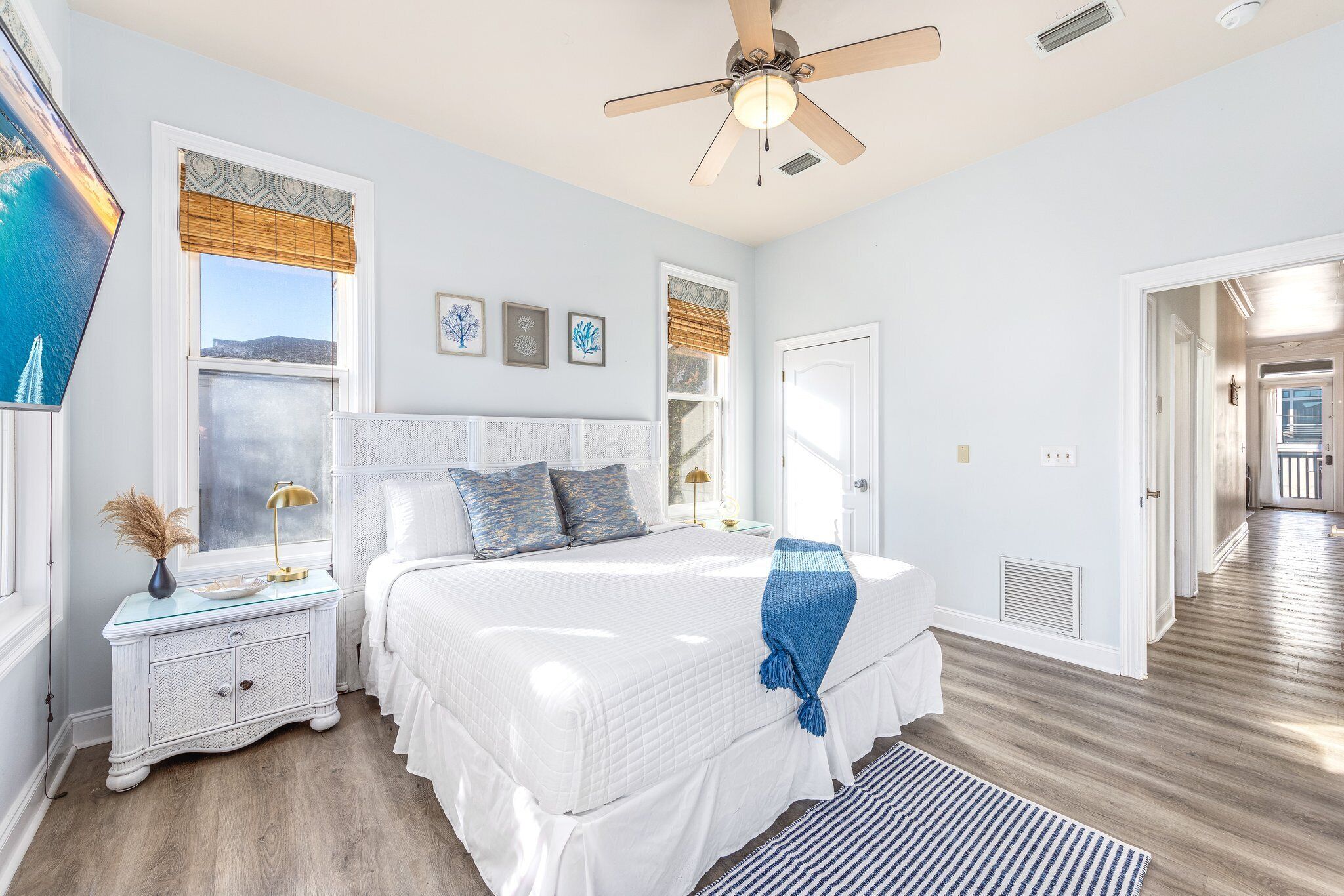 Un dormitorio con cama, mesitas de noche, ventilador de techo y vistas al exterior.