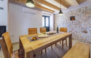 Un comedor con una mesa de madera, sillas y una pared de piedra.