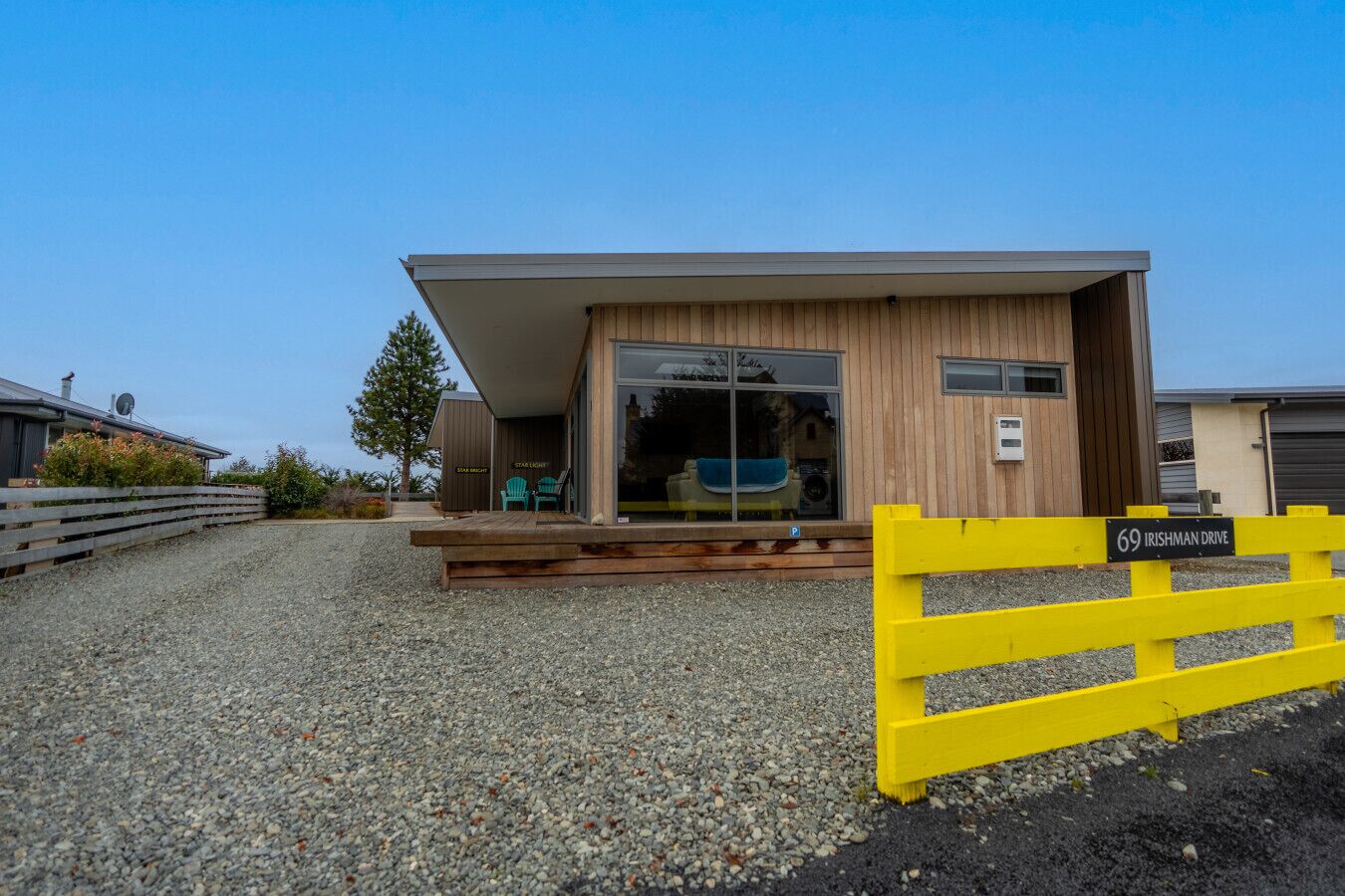 Um edifício moderno com fachada de madeira, entrada coberta e portão amarelo.
