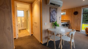 A modern interior with a white dining table and chairs, a potted plant, and a clock on the wall. - The Starlight Townhouse (Twizel)