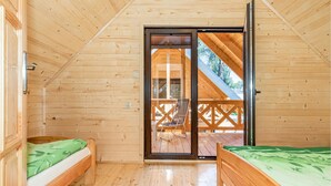 A wooden cabin with two beds, a sliding glass door to a balcony, and a view of the outside. - Nice home in Pobierowo with WiFi (Pobierowo)