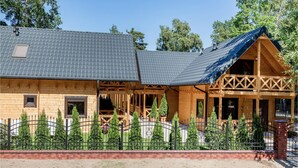 A wooden cabin with a sloped roof, a covered porch, and a fenced garden area. - Nice home in Pobierowo with WiFi (Pobierowo)