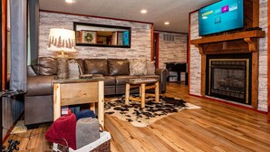 Una sala de estar moderna con chimenea, sofá de cuero, mesa de centro de madera y un televisor de pantalla plana sobre la chimenea.