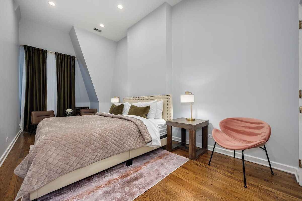 A modern bedroom with a bed, bedside tables, a chair, and a view of the outdoors.