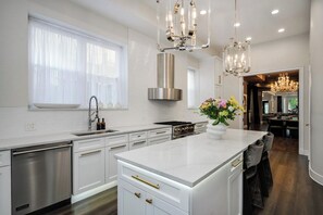 Una cocina moderna con armarios blancos, electrodomésticos de acero inoxidable y una isla central.