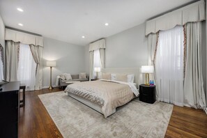 A hotel room with a large bed, bedside tables, a desk, and a lamp.