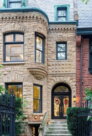 A corner building with stone facade, multiple windows, and a black front door with decorative elements.