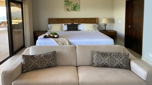 A hotel room with a large bed, a sofa with patterned cushions, a bedside table with a lamp, and a view of the outdoors. - Casita at Vista Del Paraiso-Incredable central valley view (Atenas)