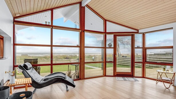 A spacious room with large windows offering a view of the beach and the sea. - Nice home in Sjølund with sauna (Sjølund)