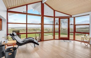 Een ruime kamer met grote ramen en uitzicht op het strand en de zee.