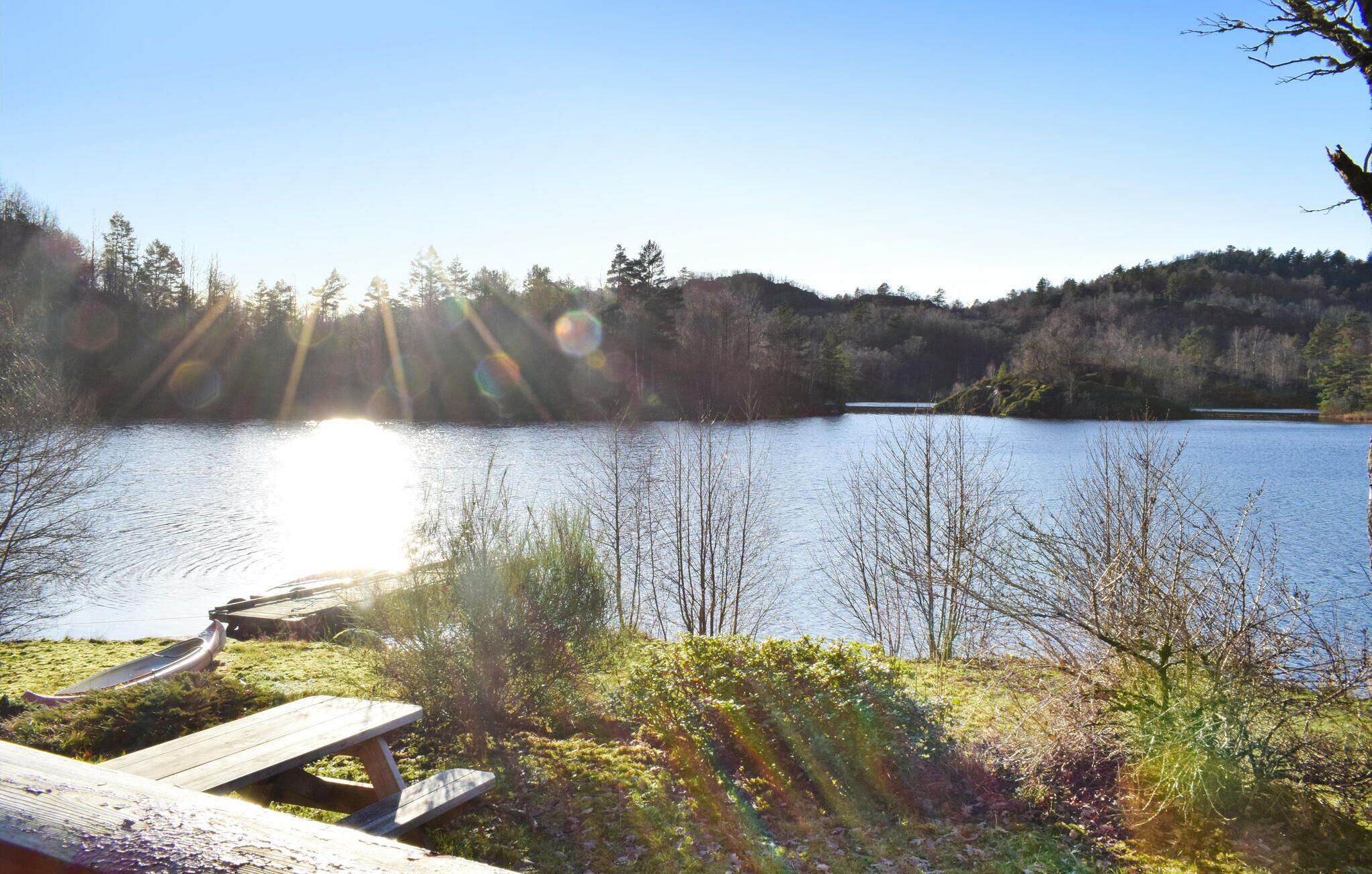 A lakeside picnic area with a wooden bench and a picnic table.