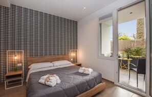 Ein modernes Schlafzimmer mit einem großen Bett, einer karierten Wand und Blick ins Freie.