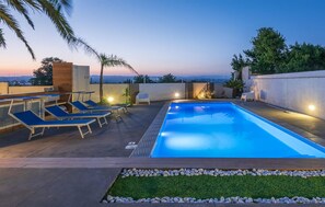 Ein Pool auf dem Dach mit Liegestühlen und Blick auf die Stadt im Abenddämmerung.