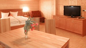 Ein Holzhüttenraum mit einem Bett, einem Fernseher und einem Tisch mit Blumen.