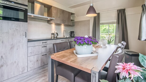 A modern kitchen with a wooden table, chairs, and a large flower vase. - Stunning home in Den Ham with WiFi (Den Ham)